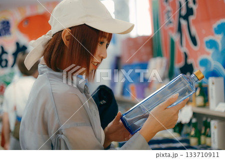 店内でボトルを手に取り眺める女性 店内でボトルを手に取り眺める女性 133710911