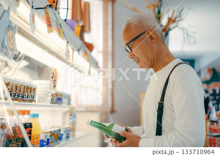 店内で商品を手に取って確かめる男性 133710964