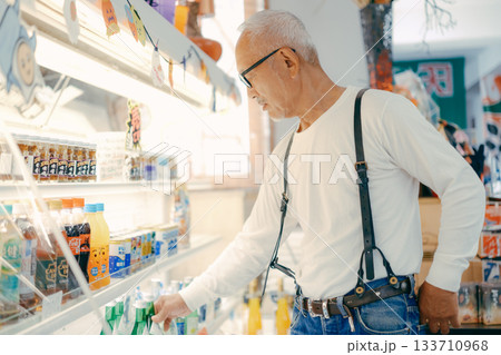 店内で商品を手に取って確かめる男性 133710968