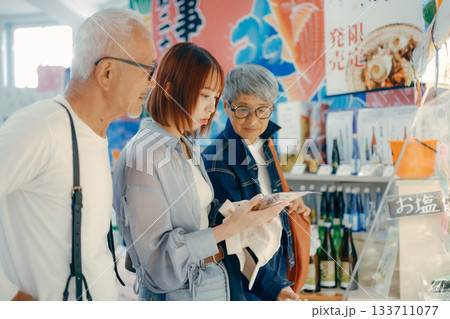 店内で商品を見ながら話す三人の姿 133711077