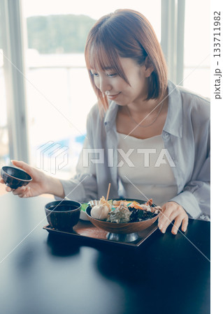 海鮮丼を前にした20代女性のランチ前シーン 海鮮丼を前にした20代女性のランチ前シーン 133711982