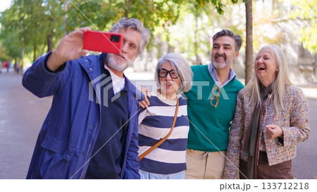 Happy senior friends taking a group selfie outdoors Happy senior friends taking a group selfie outdoors 133712218