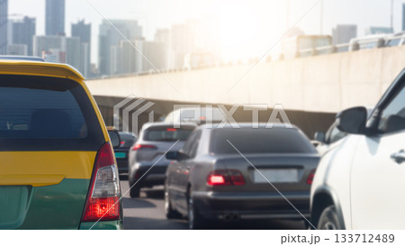 Rear side of taxi car van yellow mix green color with turn on brake light. Traffic congestion on the expressway. Heavy traffic conditions in Bangkok. Overpass with a tall building background. 133712489