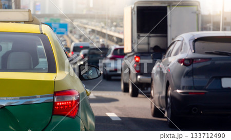 Rear side of taxi sedan car yellow mix green color with turn on brake light. Traffic congestion on the expressway at day time. Heavy traffic conditions in Bangkok Thailand. Rear side of taxi sedan car yellow mix green color with turn on brake light. Traffic congestion on the expressway at day time. Heavy traffic conditions in Bangkok Thailand. 133712490