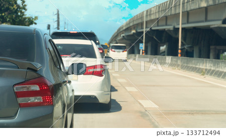 Car driving on the concrete road. Several cars were moving forward. There was a concrete overpass on the side. Under the bright sunlight during the day. Car driving on the concrete road. Several cars were moving forward. There was a concrete overpass on the side. Under the bright sunlight during the day. 133712494