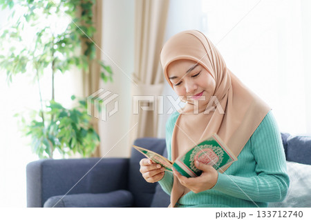 Asian beautiful muslim woman is holding the Holy Koran. Asian beautiful muslim woman is holding the Holy Koran. 133712740