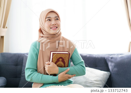 Asian beautiful muslim woman is holding the Holy Koran. Asian beautiful muslim woman is holding the Holy Koran. 133712743
