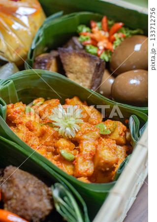 Indonesian Potato Balado, Bacem Eggs, Bacem Tempeh, and Beef Rendang Served in Banana Leaf Containers Inside a Traditional Woven Bamboo Basket, Authentic Southeast Asian Cuisine with Rich Textures and Indonesian Potato Balado, Bacem Eggs, Bacem Tempeh, and Beef Rendang Served in Banana Leaf Containers Inside a Traditional Woven Bamboo Basket, Authentic Southeast Asian Cuisine with Rich Textures and 133712756