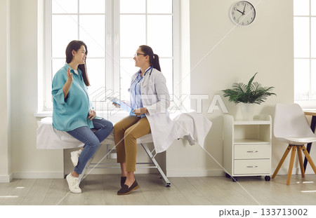 Smiling happy pregnant woman visiting her obstetrician doctor in maternity clinic. Smiling happy pregnant woman visiting her obstetrician doctor in maternity clinic. 133713002