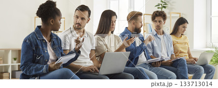 Group of diverse people sitting in office, discussing work and using cell phones and laptops Group of diverse people sitting in office, discussing work and using cell phones and laptops 133713014