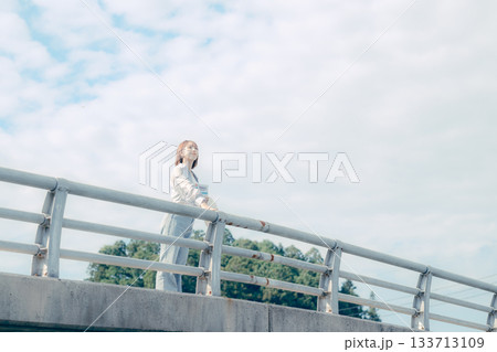 橋の上で空を見上げる20代女性のポートレート 133713109