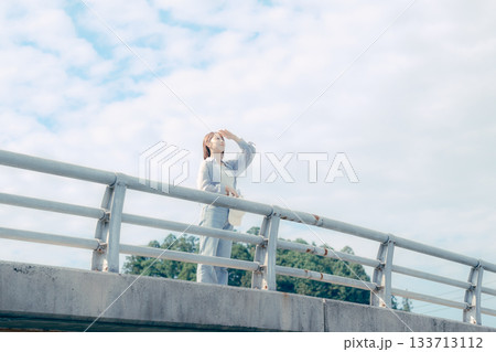 橋の上で空を見上げる20代女性のポートレート 133713112