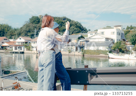 60代シニアと20代女性が旅先でスマホを見るシーン 133713255