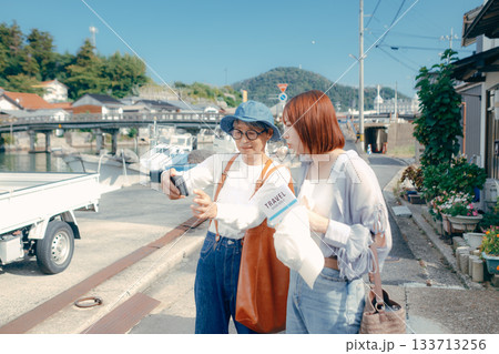 60代シニアと20代女性が旅先でスマホを見るシーン 60代シニアと20代女性が旅先でスマホを見るシーン 133713256