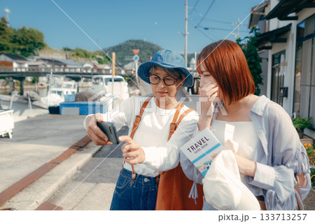 60代シニアと20代女性が旅先でスマホを見るシーン 60代シニアと20代女性が旅先でスマホを見るシーン 133713257