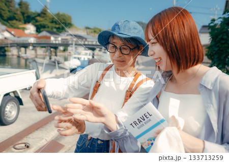 60代シニアと20代女性が旅先でスマホを見るシーン 60代シニアと20代女性が旅先でスマホを見るシーン 133713259