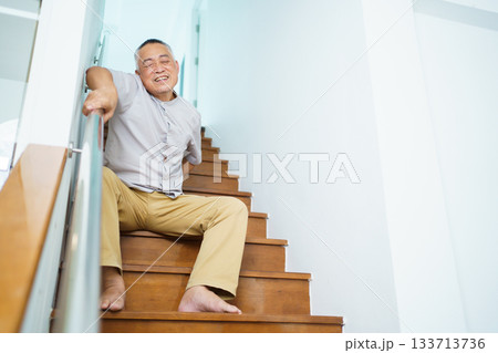Elderly Asian man has an accident while he was walking on the staircase at home. 133713736