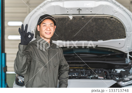 自動車整備工場のピットで自動車のエンジンルームの前に立つ整備士,メカニックの男性スタッフ 自動車整備工場のピットで自動車のエンジンルームの前に立つ整備士,メカニックの男性スタッフ 133713748