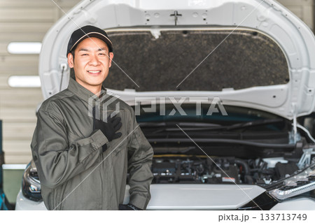 自動車整備工場のピットで自動車のエンジンルームの前に立つ整備士,メカニックの男性スタッフ 133713749