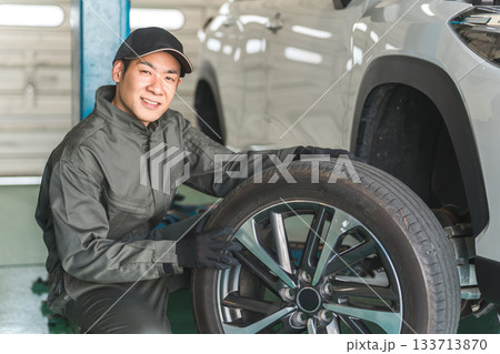 リフトアップした車のタイヤ交換をする整備士の男性 133713870