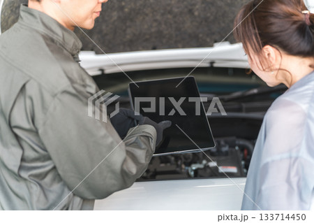 車のエンジンルームで女性客に説明,解説をする整備士,メカニックの男性スタッフ 133714450
