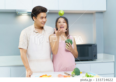 Husband and pregnant wife making a food together. Husband and pregnant wife making a food together. 133714622