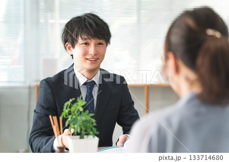 ショールーム・商談スペースで接客する若いアジア人ビジネスマンと女性客 ショールーム・商談スペースで接客する若いアジア人ビジネスマンと女性客 133714680