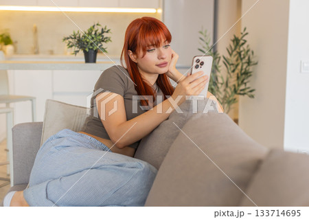 Young woman bored scrolls news on smartphone dissatisfied shows fatigue and emotional exhaustion meh 133714695