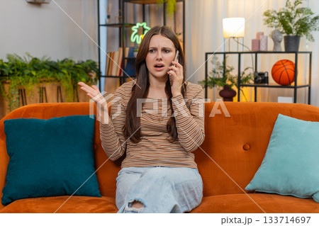 Young woman argues on smartphone frowns sharp hand moves raises voice and speaks fast in tense call 133714697