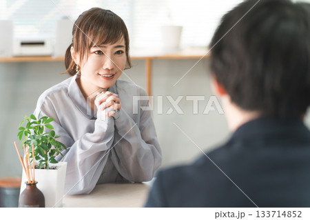 商談のテーブルで営業マンの話を聞く女性客 133714852