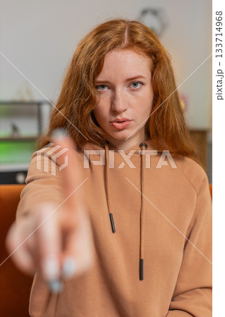Displeased upset young woman sitting on sofa reacting to unpleasant awful idea, shake finger No 133714968