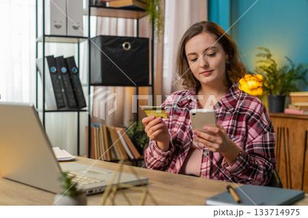 Woman using bank credit card and smartphone for online shopping payments transaction at home office Woman using bank credit card and smartphone for online shopping payments transaction at home office 133714975