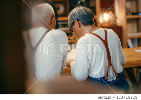 カフェで雑誌を楽しむシニア夫婦のくつろぎ時間 133715219