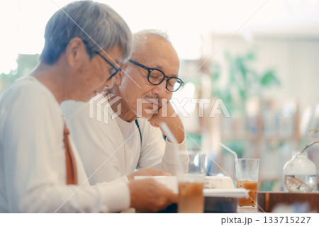 カフェで雑誌を楽しむシニア夫婦のくつろぎ時間 133715227