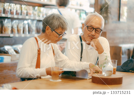 カフェで雑誌を楽しむシニア夫婦のくつろぎ時間 133715231