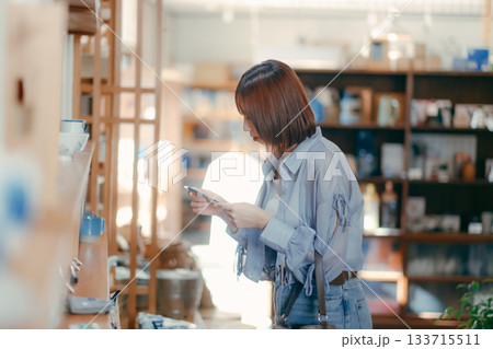 カフェ雑貨を手に取る20代女性のローカル散策シーン カフェ雑貨を手に取る20代女性のローカル散策シーン 133715511