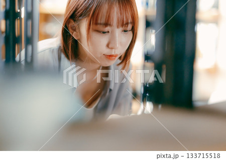 カフェ雑貨を手に取る20代女性のローカル散策シーン 133715518