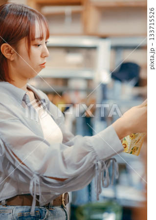 カフェ雑貨を手に取る20代女性のローカル散策シーン 133715526