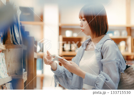 カフェ雑貨を手に取る20代女性のローカル散策シーン カフェ雑貨を手に取る20代女性のローカル散策シーン 133715530