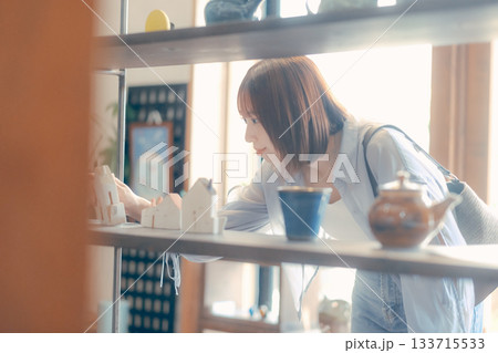 カフェ雑貨を手に取る20代女性のローカル散策シーン カフェ雑貨を手に取る20代女性のローカル散策シーン 133715533