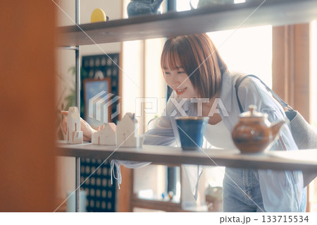 カフェ雑貨を手に取る20代女性のローカル散策シーン カフェ雑貨を手に取る20代女性のローカル散策シーン 133715534