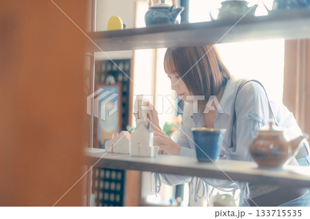 カフェ雑貨を手に取る20代女性のローカル散策シーン カフェ雑貨を手に取る20代女性のローカル散策シーン 133715535