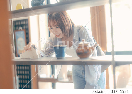 カフェ雑貨を手に取る20代女性のローカル散策シーン カフェ雑貨を手に取る20代女性のローカル散策シーン 133715536