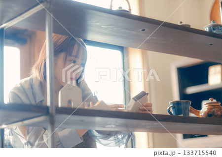 カフェ雑貨を手に取る20代女性のローカル散策シーン カフェ雑貨を手に取る20代女性のローカル散策シーン 133715540