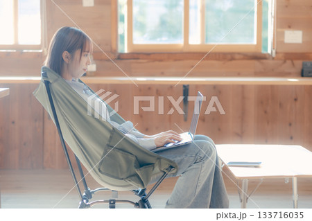 椅子にゆったり座って作業する20代女性のワークシーン 133716035