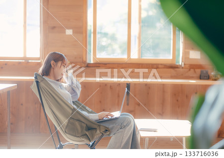 椅子にゆったり座って作業する20代女性のワークシーン 椅子にゆったり座って作業する20代女性のワークシーン 133716036