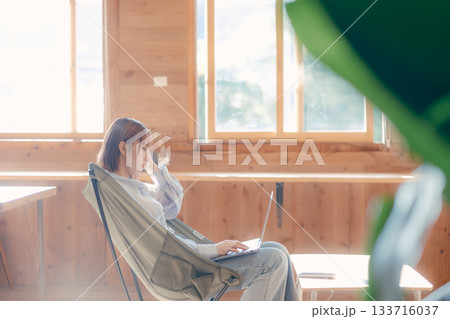 椅子にゆったり座って作業する20代女性のワークシーン 133716037