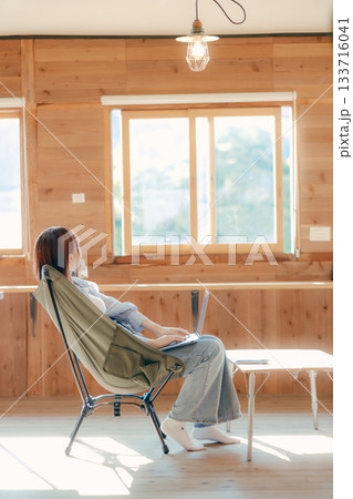 椅子にゆったり座って作業する20代女性のワークシーン 椅子にゆったり座って作業する20代女性のワークシーン 133716041