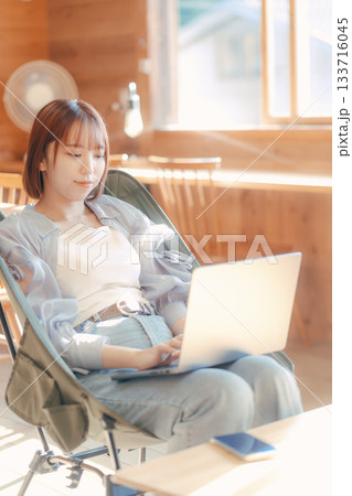 椅子にゆったり座って作業する20代女性のワークシーン 133716045
