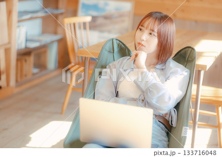 椅子にゆったり座って作業する20代女性のワークシーン 椅子にゆったり座って作業する20代女性のワークシーン 133716048